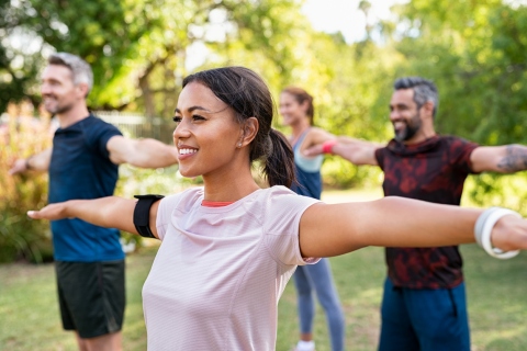 Group of diverse individuals exercising in a park - managing vital signs for healthier lifestyle.