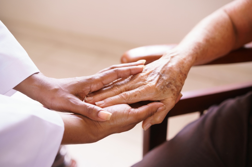 close-up-of-doctor's-hand-holding-hand-of-elderly-patient-while-both-sit-face-to-face