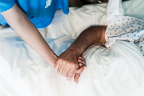 Understanding patients' rights - Doctor holding the hand of a male patient in a hospital.