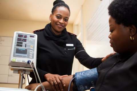 woman using machine to take blood pressure of seated woman indoors