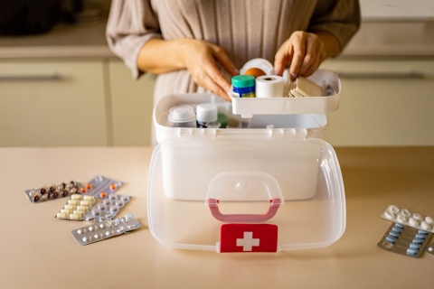 Woman putting different medical items in her home's medical emergency kit.