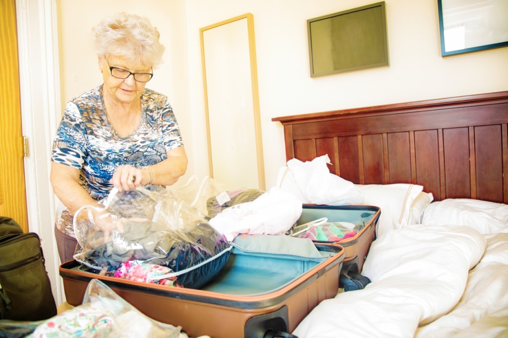 Senior woman placing clothes in a luggage using plastic bags to prevent bed bug infestation.